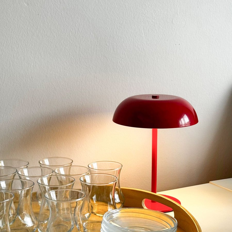 Luminária vermelha sobre uma mesa com copos de vidro