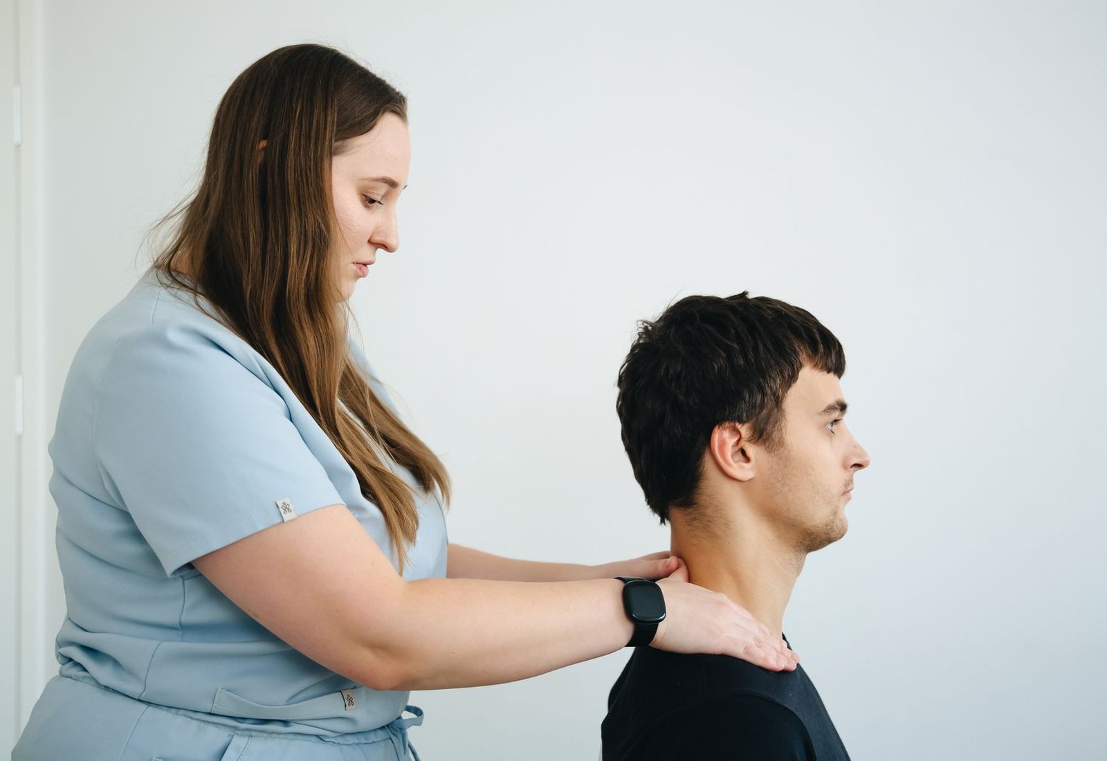 Fisioterapeuta avaliando a cervical de um paciente em um consultório claro