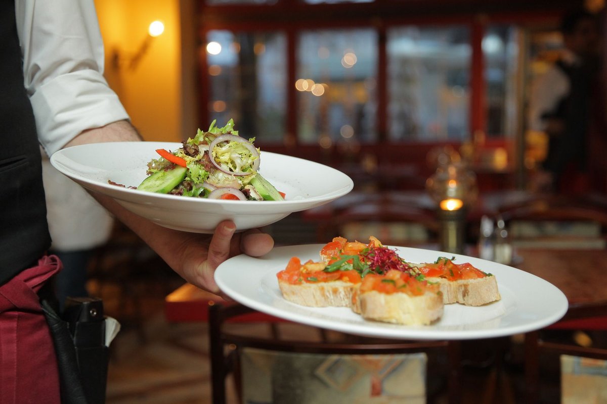 Garçom servindo uma mesa de restaurante